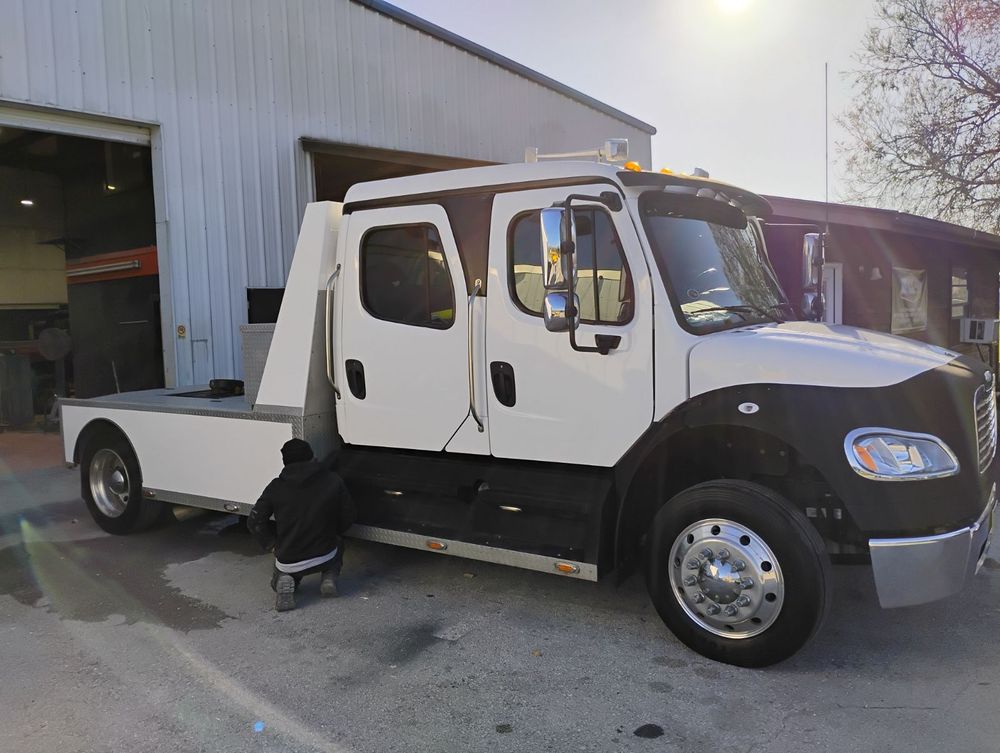 White and black Freightliner crew cab pickup truck parked at industrial facility