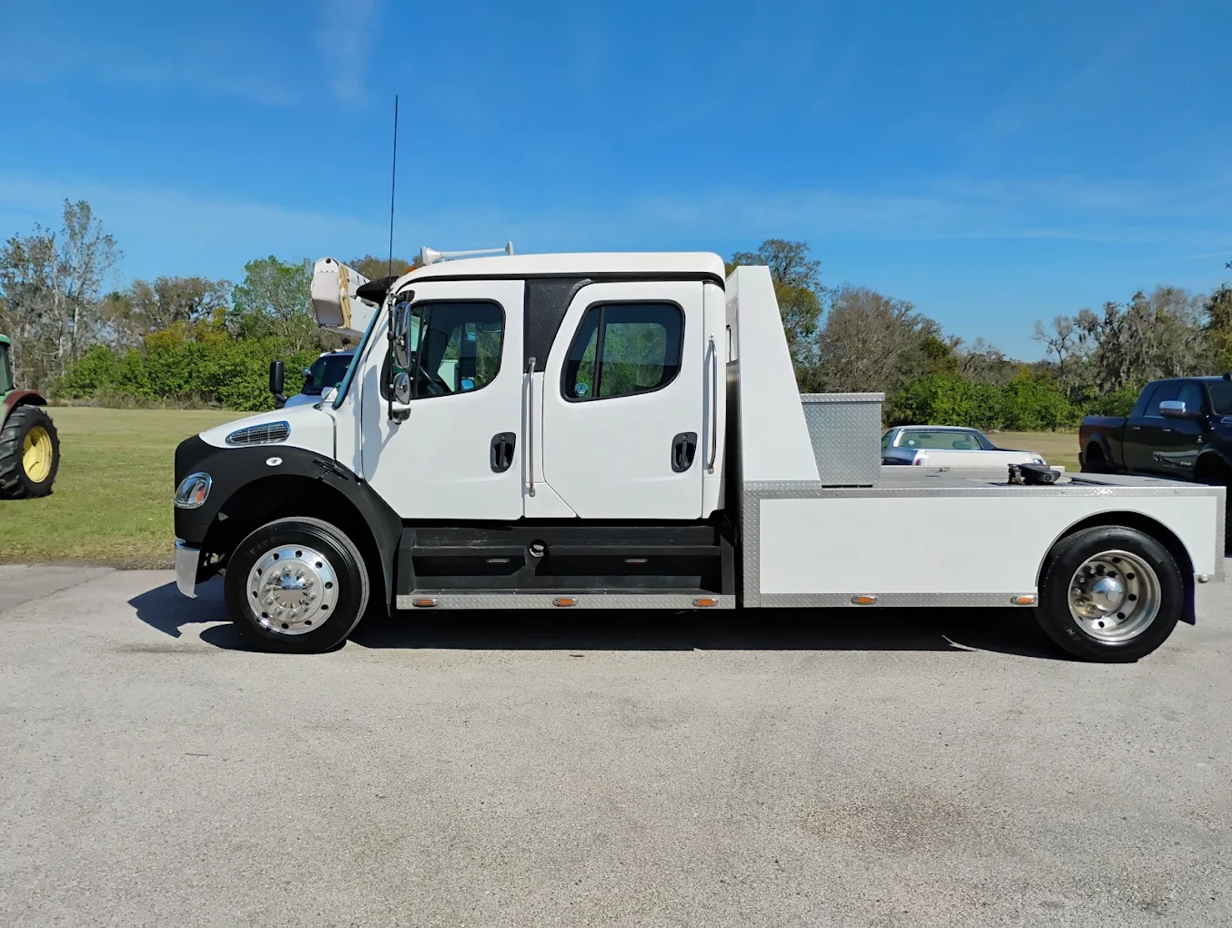 White and black Freightliner commercial pickup truck with crew cab parked on asphalt