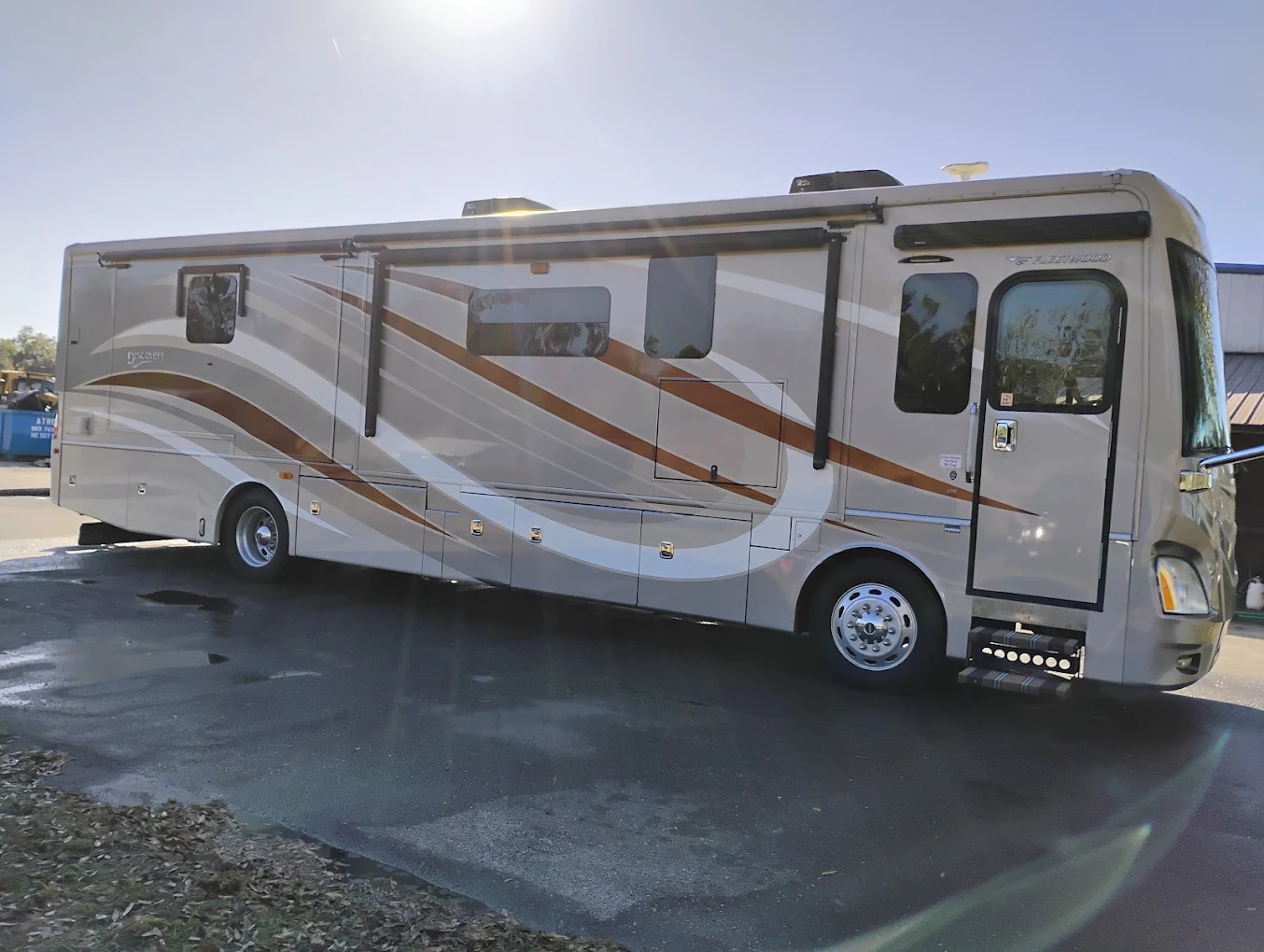 White and brown motorhome with extended awning parked in lot