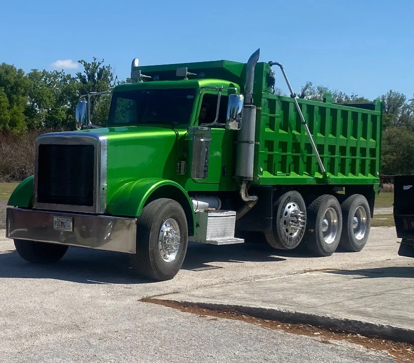 Bright green dump truck with open bed parked in lot on clear day