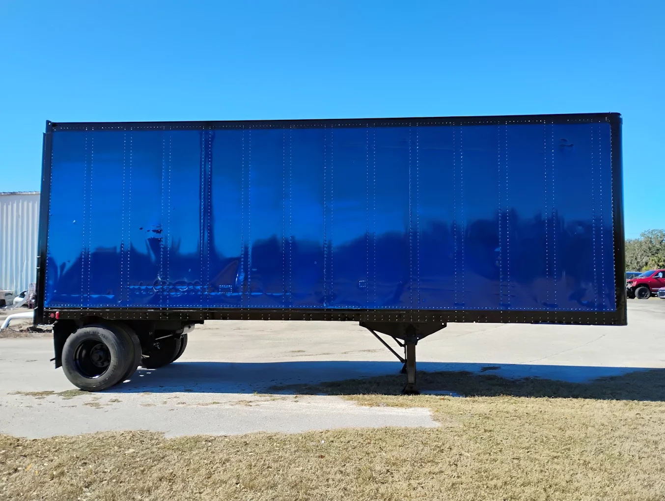 Blue semi-truck trailer parked in lot under clear sky