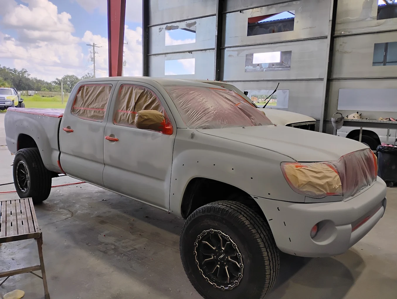 White pickup truck with protective coverings in industrial garage bay