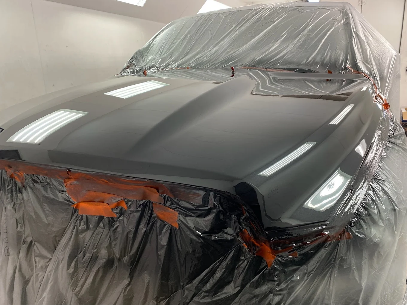 Car covered with protective plastic sheeting in spray paint booth