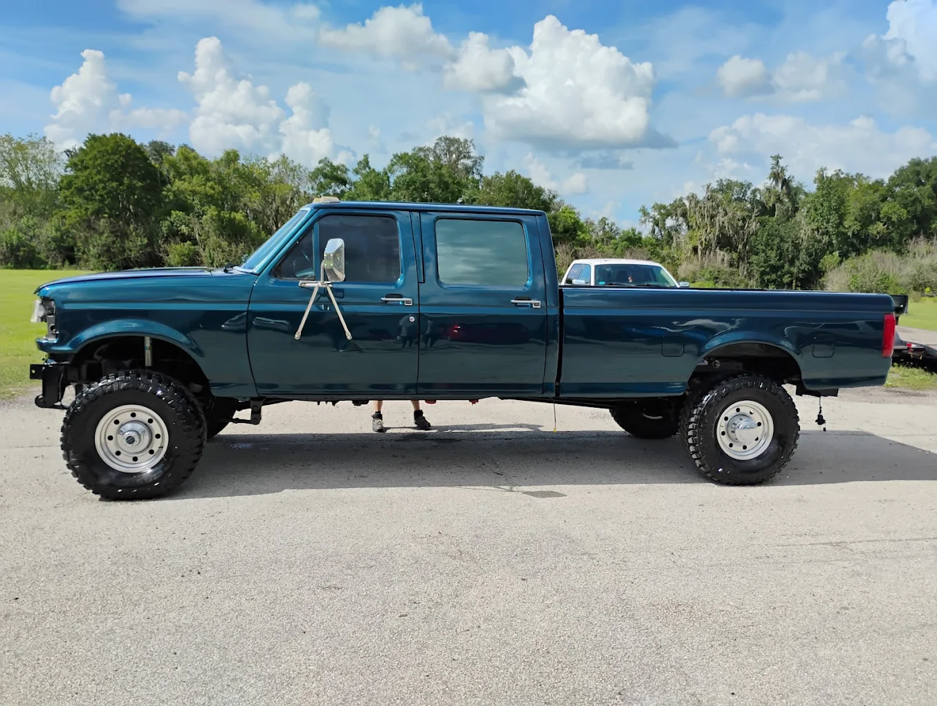 Lifted blue Ford F-250 crew cab pickup truck with oversized tires parked on asphalt