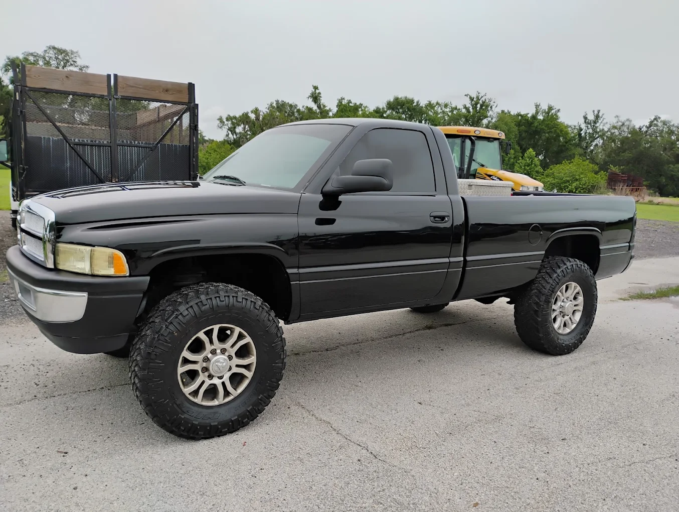 Black lifted pickup truck with custom wheels parked on asphalt lot