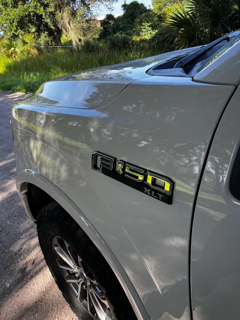 White Ford F-150 XLT pickup truck with custom yellow badging parked outdoors